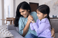 Mother and daughter laughing together on a sofa, lifestyle for UMF 24+ MGO 1122+ Manuka honey