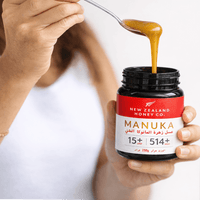 Person lifting honey from a UMF 15+ MGO 514+ Manuka honey jar held in their hand