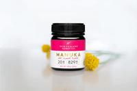UMF 20+ MGO 829+ Manuka honey jar styled on a counter with yellow billy buttons flowers