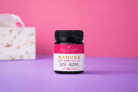 UMF 20+ MGO 829+ Manuka honey jar styled on a purple surface beside a tissue box