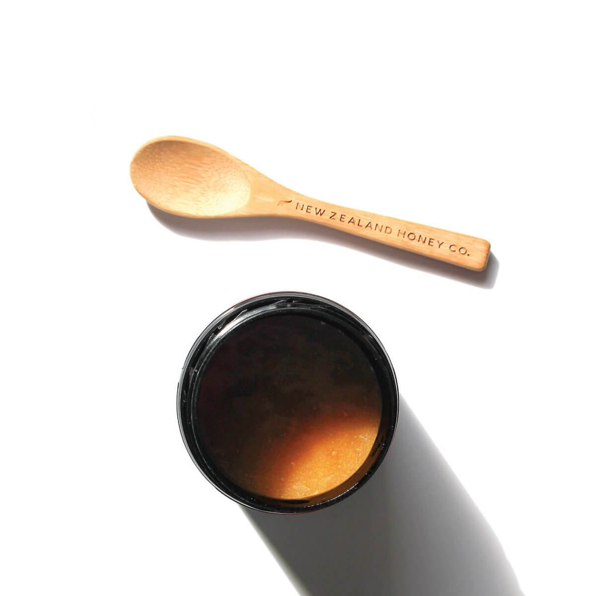 Bamboo Daily Spoon next to an open Manuka honey jar, top-down view