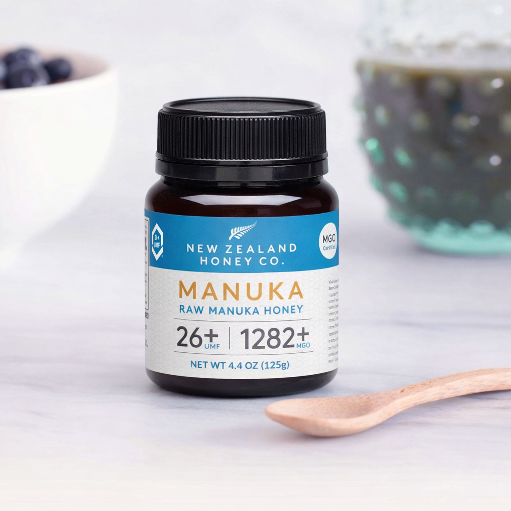 UMF 26+ MGO 1282+ Manuka honey mini jar with bamboo spoon on a marble counter