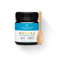 UMF 26+ MGO 1282+ Manuka honey 250g jar with bamboo spoon on black background