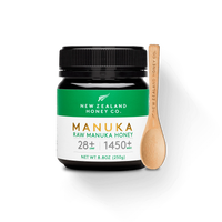 UMF 28+ MGO 1450+ Manuka honey 250g jar with branded bamboo honey spoon on white