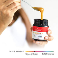 Spoon lifting honey from an open UMF 15+ MGO 514+ Manuka honey jar held in two hands